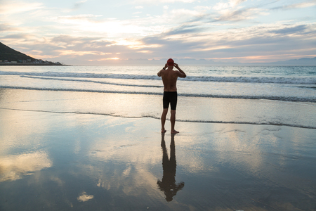 Senior man, aged 65, preparing to swim in the sea at dawnの写真素材