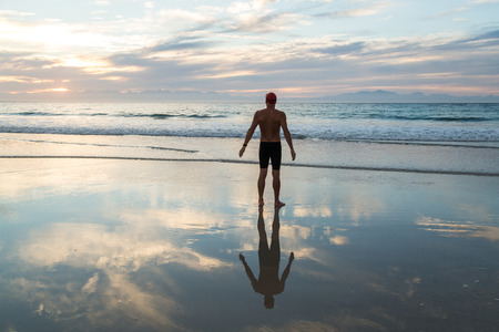 Senior man, aged 65, preparing to swim in the sea at dawnの写真素材