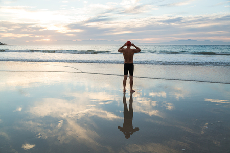 Senior man, aged 65, preparing to swim in the sea at dawnの写真素材