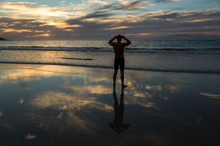 Senior man, aged 65, preparing to swim in the sea at dawnの写真素材