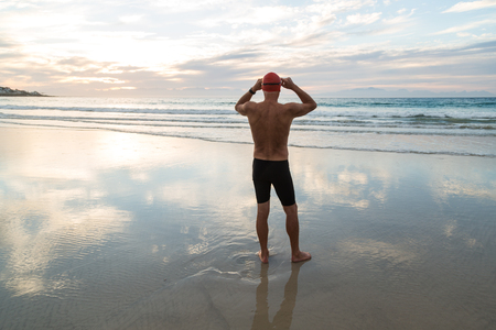Senior man, aged 65, preparing to swim in the sea at dawnの写真素材
