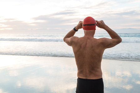 Senior man, aged 65, preparing to swim in the sea at dawnの写真素材
