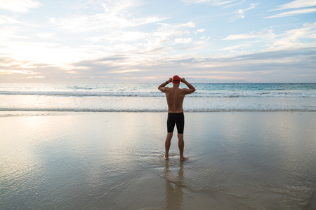 Senior man, aged 65, preparing to swim in the sea at dawnの写真素材