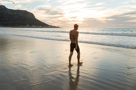 Senior man, aged 65, preparing to swim in the sea at dawnの写真素材