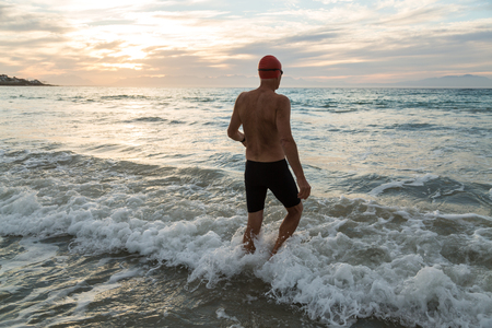 Senior man, aged 65, preparing to swim in the sea at dawnの写真素材