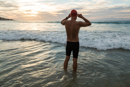 Senior man, aged 65, preparing to swim in the sea at dawnの写真素材