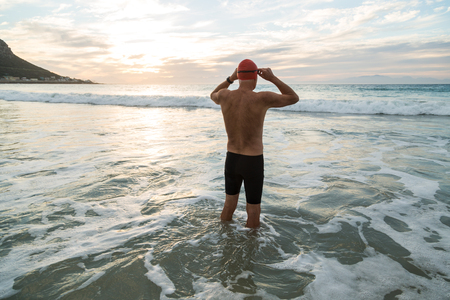 Senior man, aged 65, preparing to swim in the sea at dawnの写真素材