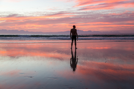 Senior man, aged 65, preparing to swim in the sea at dawnの写真素材