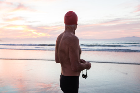 Senior man, aged 65, preparing to swim in the sea at dawnの写真素材