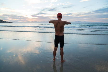 Senior man, aged 65, preparing to swim in the sea at dawnの写真素材