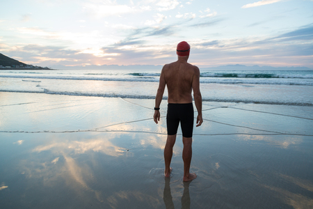 Senior man, aged 65, preparing to swim in the sea at dawnの写真素材