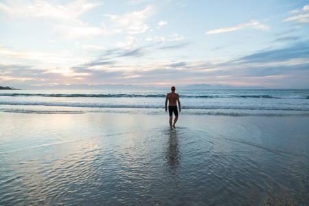 Senior man, aged 65, preparing to swim in the sea at dawnの写真素材