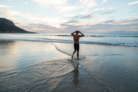 Senior man, aged 65, preparing to swim in the sea at dawnの写真素材