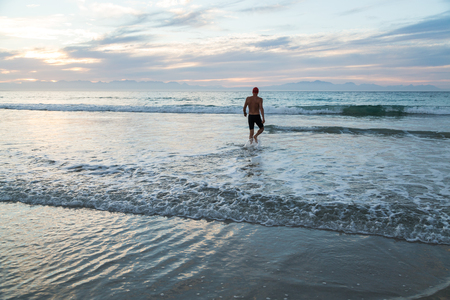 Senior man, aged 65, preparing to swim in the sea at dawnの写真素材
