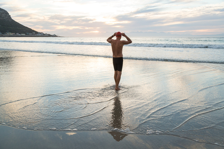 Senior man, aged 65, preparing to swim in the sea at dawnの写真素材