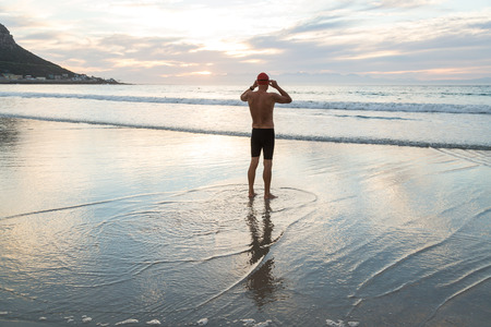 Senior man, aged 65, preparing to swim in the sea at dawnの写真素材