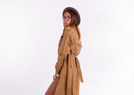 Woman in model pose wearing autumn coat with hat and eyeglasses, over whiteの写真素材
