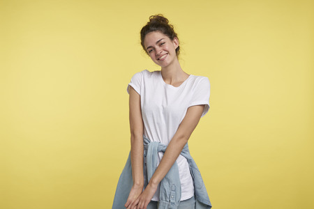 A portrait of beautiful shy student girl isolated over yellow backgroundの写真素材
