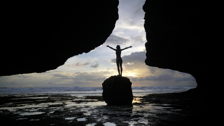 Wide shot of woman s siluet on the sunset, against the oceanの写真素材