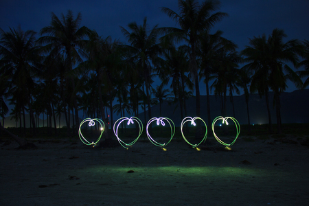 5 hearts painted on the beach with light on long time exposure of camera (bulb mode). This kind of photography is called light brush techniqueの写真素材