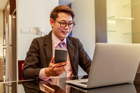 Happy smiling young man watching and working on computer laptop at homeの写真素材