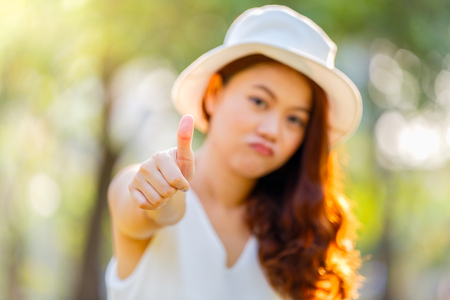 Asian woman showing thumbs-up with focus on hand on parking background