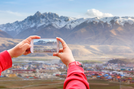 Smartphone photographing Village inclose mountain a famous landmark in Ganzi, Sichuan, China.の写真素材