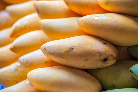 Very ripe yellow mango with skin in basket ready for sale - outdoor lighting
