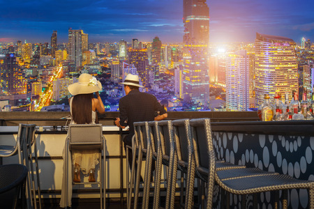 Asian lover couple enjoying look at view twilight time on top view bar and restaurant in this time beautiful colorful night at Bangkok Cityの写真素材
