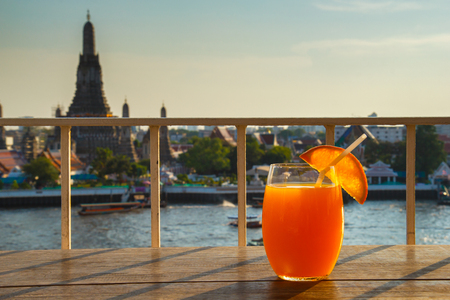Orange juice on table in rooftop bar with famous place background. Wat Arun ,Bangkok ,Thailandの写真素材