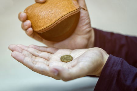 Hands holding one dollar coin and small money pouch.の写真素材