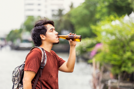 Sad single asian man drinking beer at public park.の写真素材