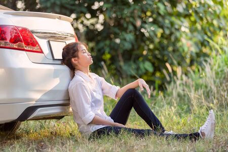 Young Asian women sitting outside car is very upset and stressedの写真素材