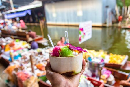 Sweet coconut ice cream in the fresh coconut and plastic spoon at Damnoen Saduak floating market, Ratchaburi, Thailandの写真素材