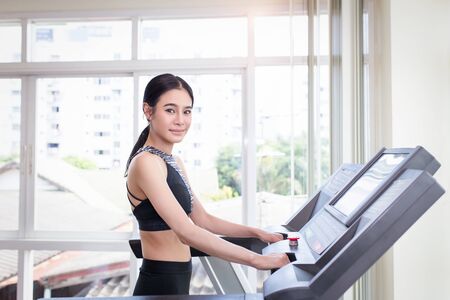 Young sports asian woman is working out in gym. Doing cardio training on treadmill.