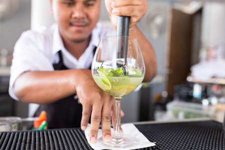 Bartender is making cocktail at counter bar.