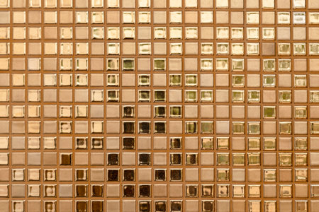 Close-up of golden-colored square glass tiles covering the bathroom wall texture as a background.の写真素材