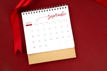 September 2025 desk calendar and red ribbon on red color background.の写真素材