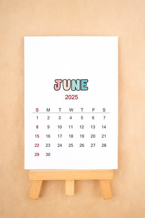 Calendar page for June 2025 with wood easel on old brown color background.の写真素材