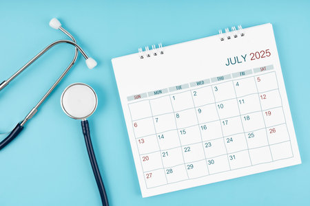 July 2025 desk calendar and stethoscope on blue color, Medical appointment concept.の写真素材