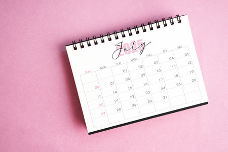 Top view of July 2025 desk calendar on pink pastel background.の写真素材