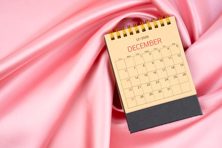 December 2026 paper desk calendar on pink color silk textile background.の写真素材