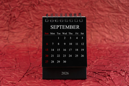 September 2026, Front view black desk calendar on crumpled red paper background.の写真素材