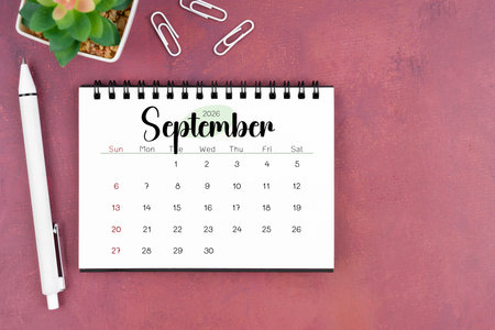 September desk calendar for 2026 year and pen on old red cover.の写真素材