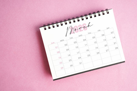Top view of March 2026 desk calendar on pink background.の写真素材