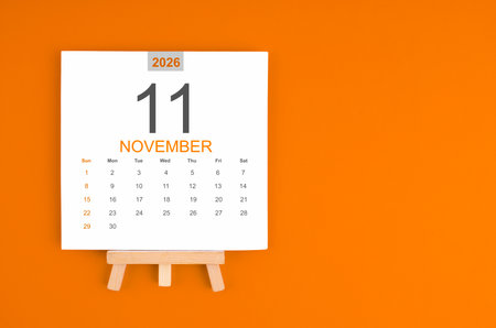 Calendar page for November 2026 with wood easel on orange background.の写真素材