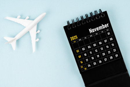 November 2025 black calendar and airplane toy on blue background.の写真素材