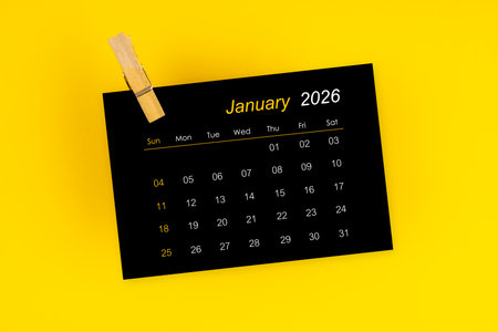 January 2026 black calendar with wooden clip on yellow background.の写真素材