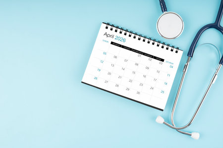 April 2026 desk calendar and stethoscope on blue, Position with copy space.の写真素材