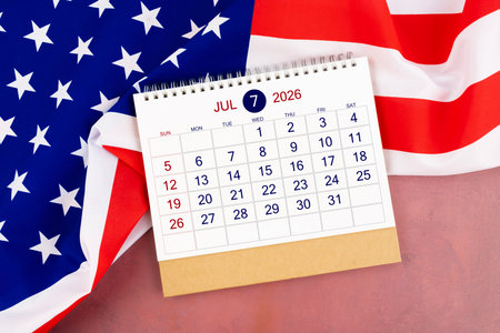 July 2026 Monthly desk calendar and United States of America flag on red wooden.の写真素材